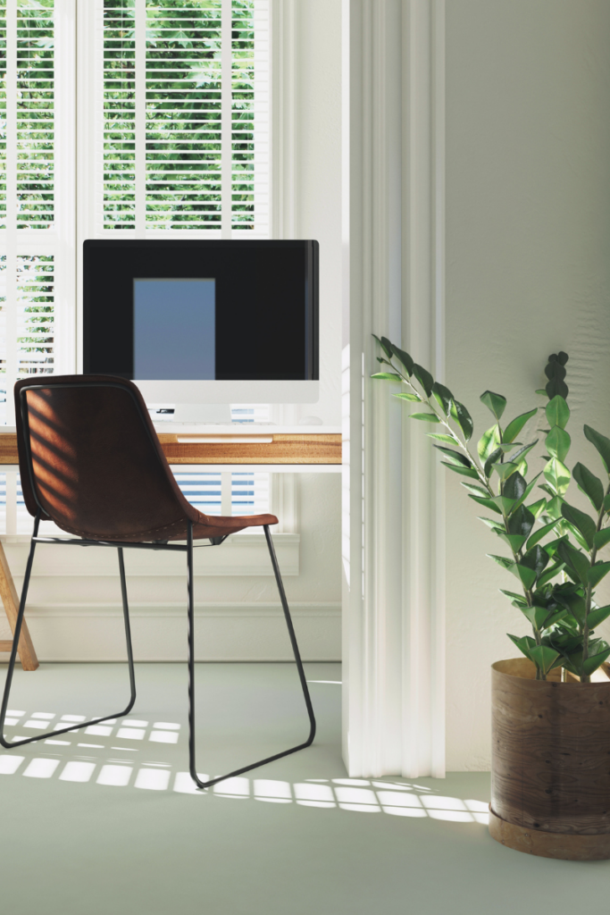 Photo of computer on desk with brown chair in front of a window with lots of light