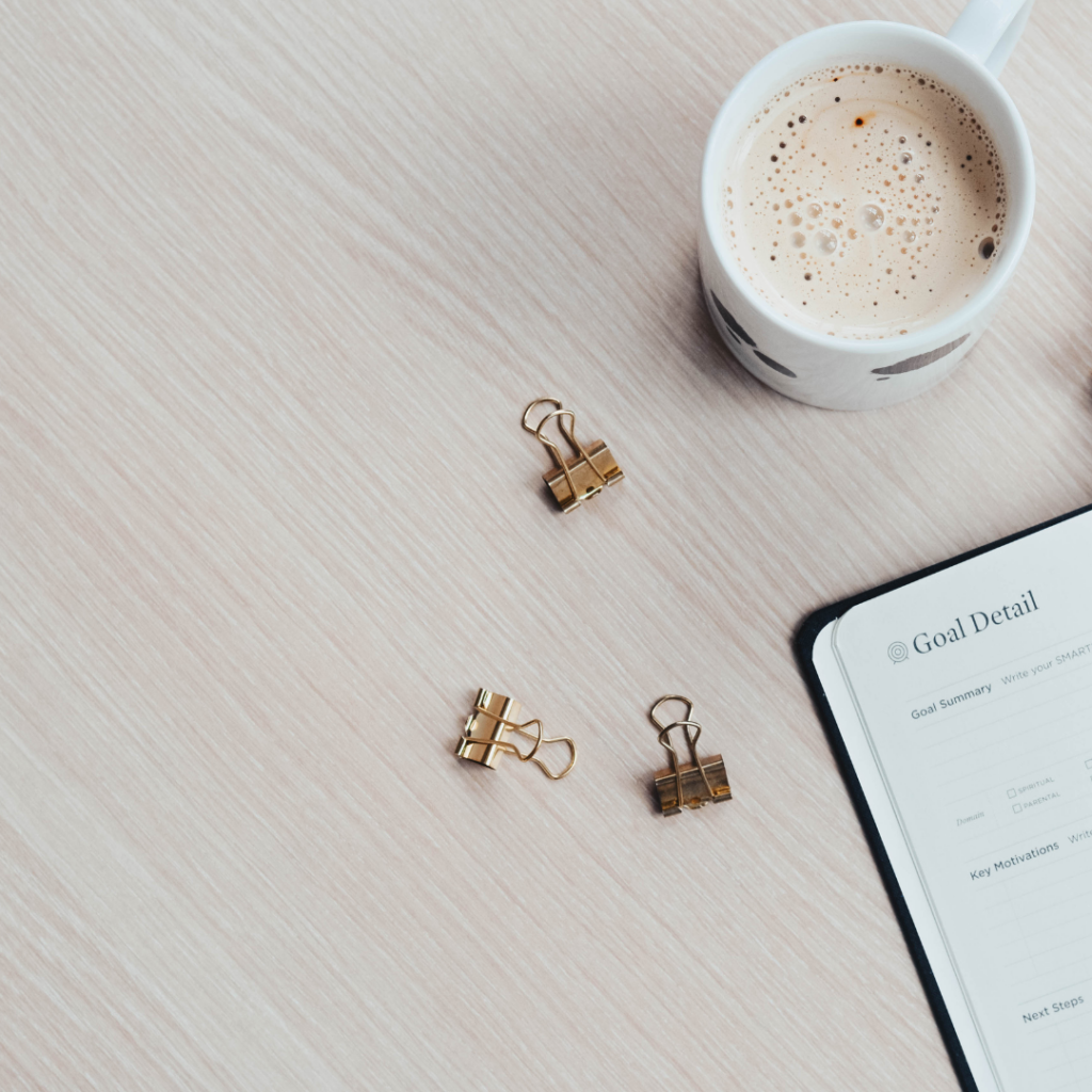 goal planner, three paper clips and coffee mug