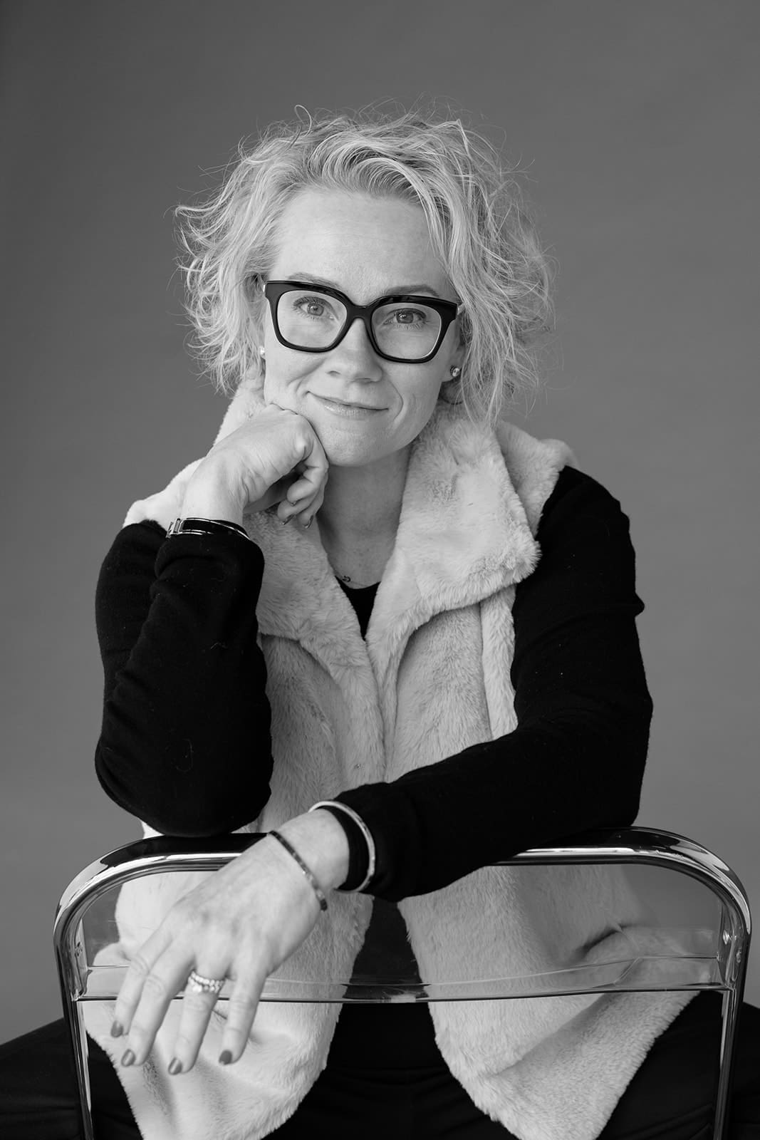 Black and white portrait of Cindy Gordon in glasses with her hand under her chin