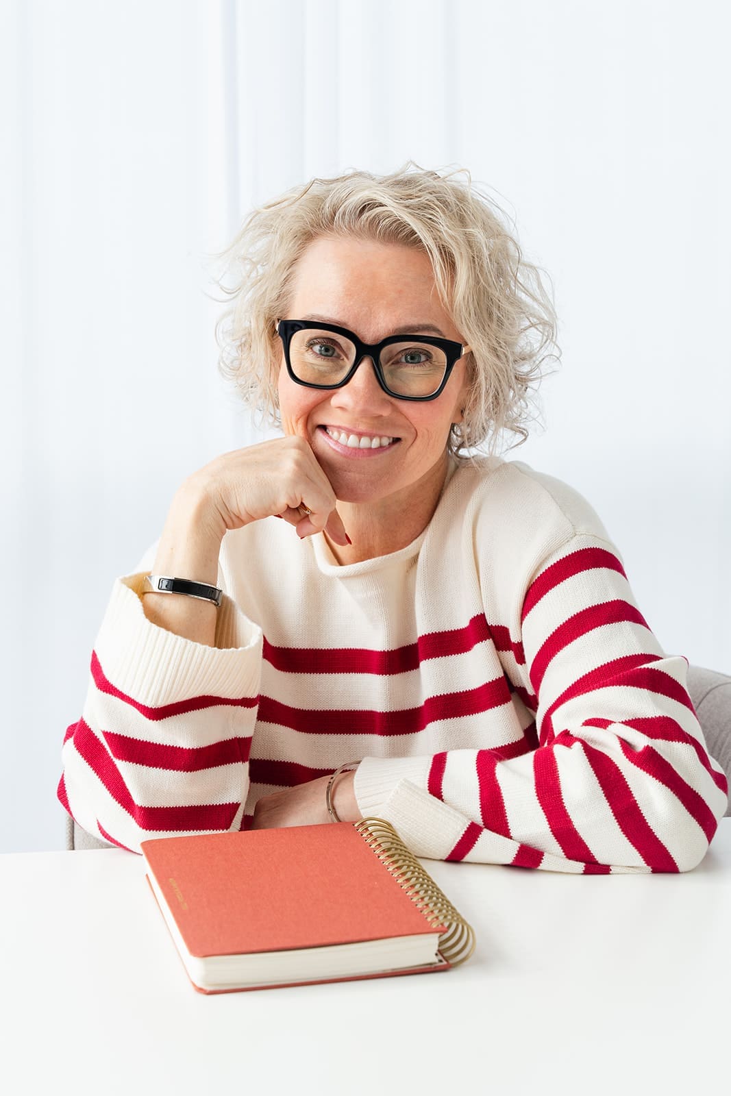 Cindy Gordon in a red striped sweater smiling with her chin resting on her hand