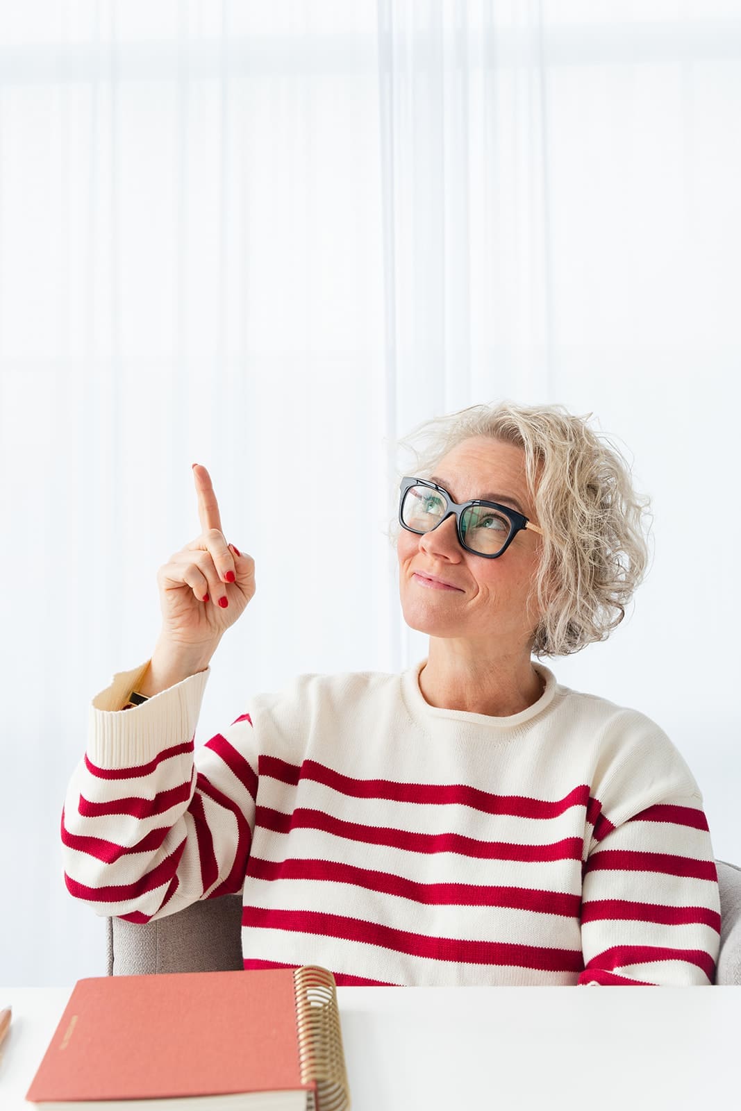 Cindy Gordon in a red striped sweater raising one finger to make a point