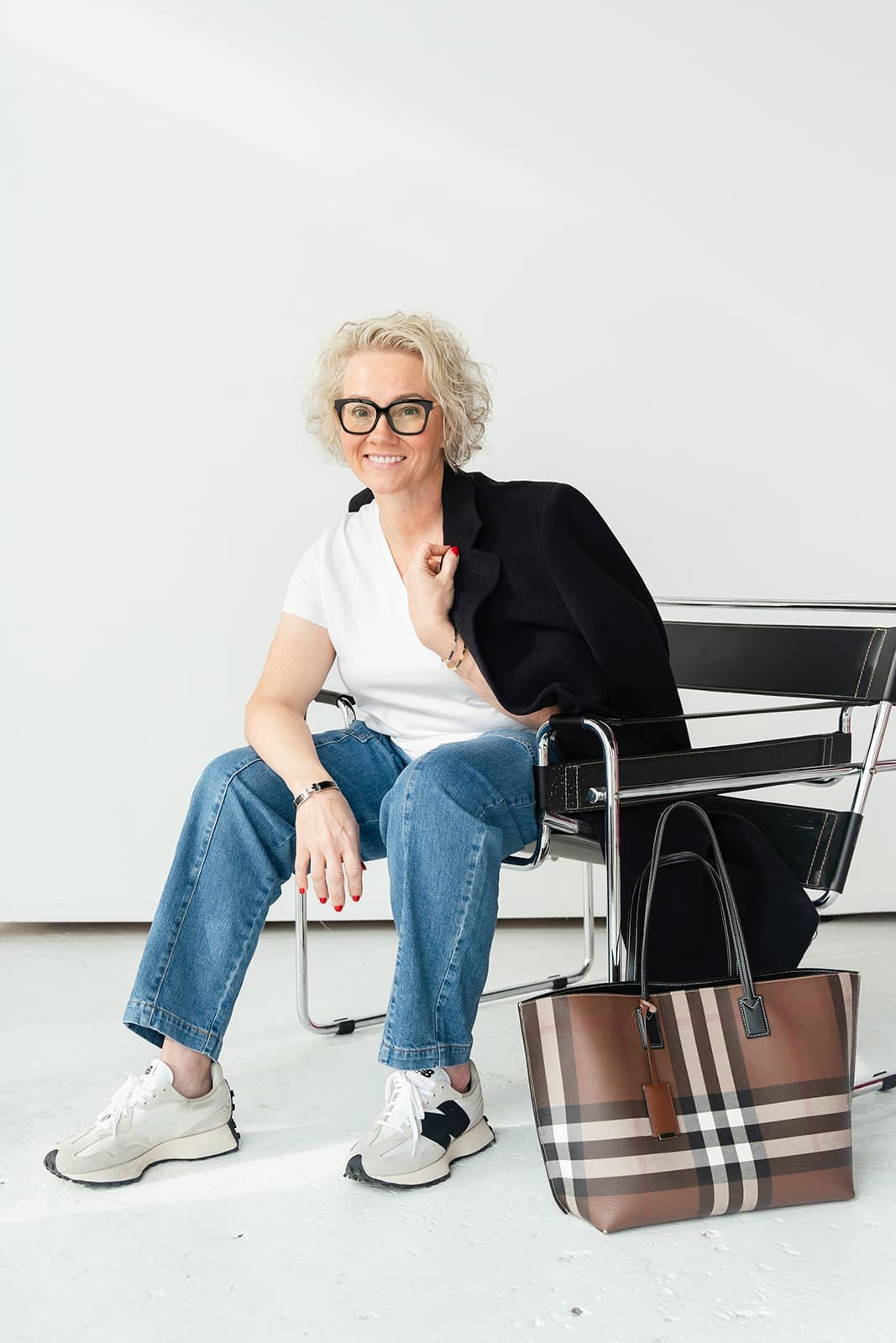 Cindy Gordon seated in jeans and a light top with a striped bag beside her chair